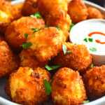 Bowl of breaded cauliflower air fryer bites with dipping sauces.