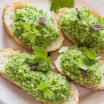 A vibrant and creamy broccoli stem pesto served in a rustic bowl, accompanied by fresh broccoli stems, garlic, and pine nuts, highlighting the natural ingredients used in the recipe.