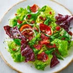 Warm killed lettuce salad with crispy bacon and green onions in a rustic bowl, drizzled with hot tangy dressing.